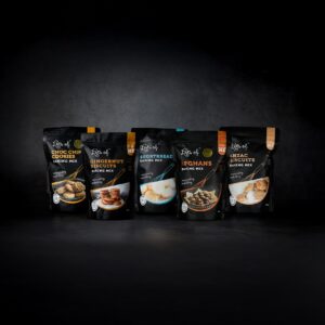 Selection of Lots of Baking Mixes cookie baking mixes including Choc Chip Cookies, Gingernut Biscuits, Shortbread, Afghans and Anzac Biscuits on a dark background.