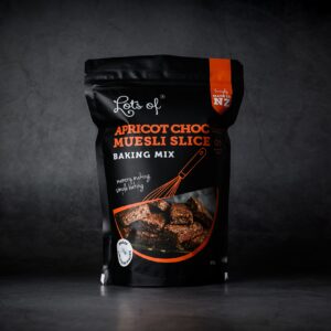 Lots of Baking Mixes Apricot Choc Museli Slice Baking Mix pouch on a dark background, New Zealand made baking mix for easy homemade chocolate slice baking.